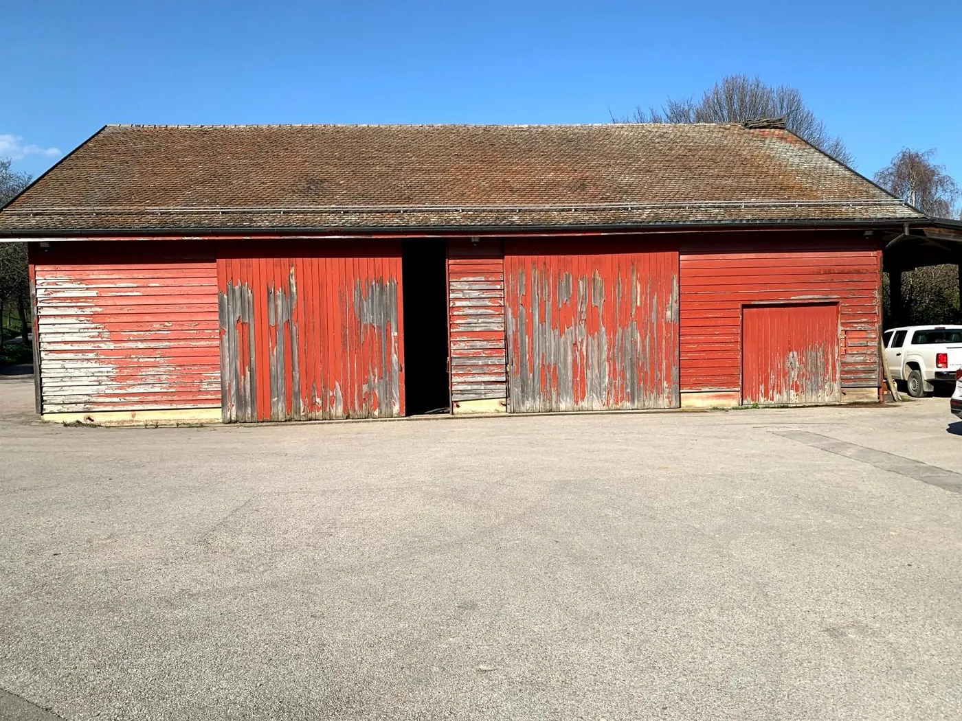 Le rural avant travaux : bardage bois rouge délavé et peinture écaillée.