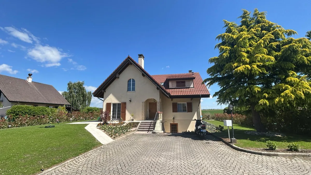 Villa avec allée pavée et grand jardin, façade remise à neuf.