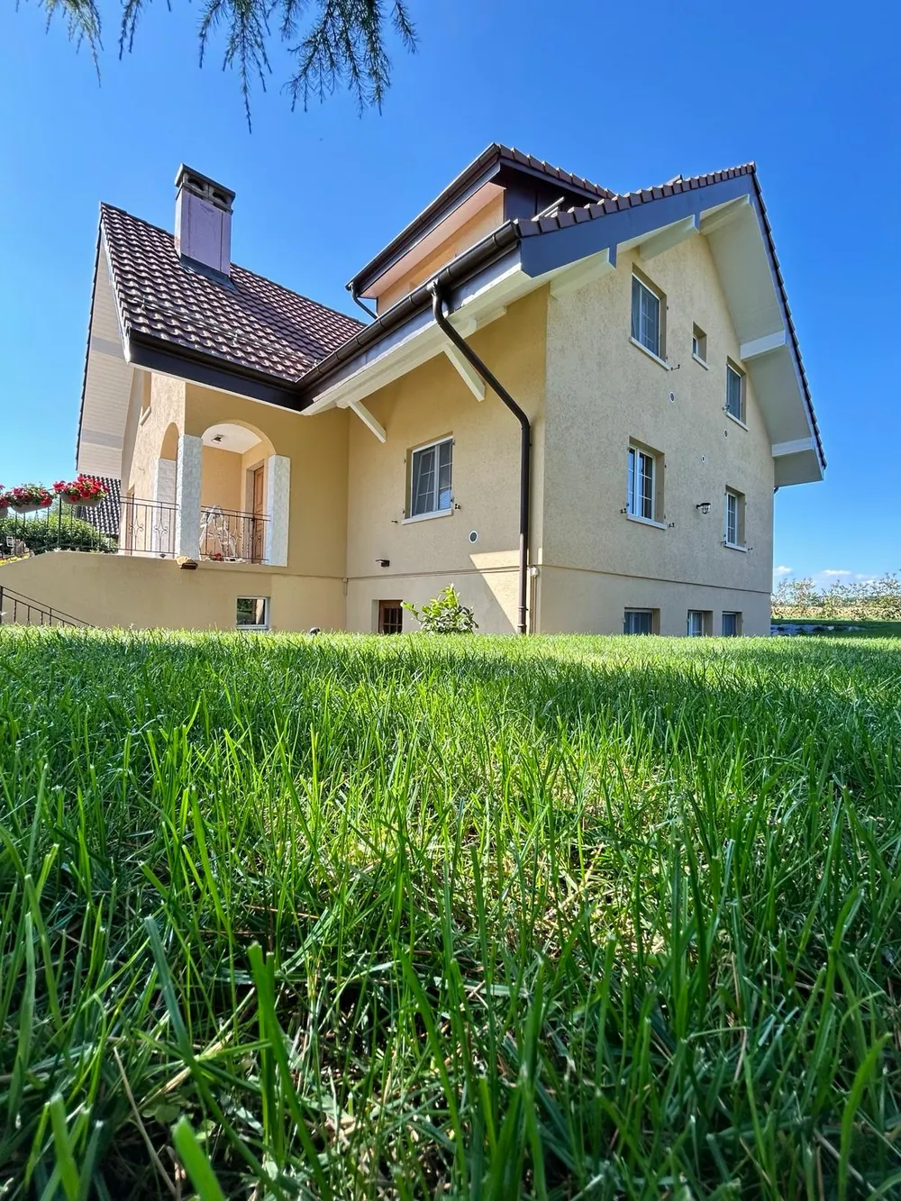 Villa au crépi jaune avec volets clairs et toit de tuiles.